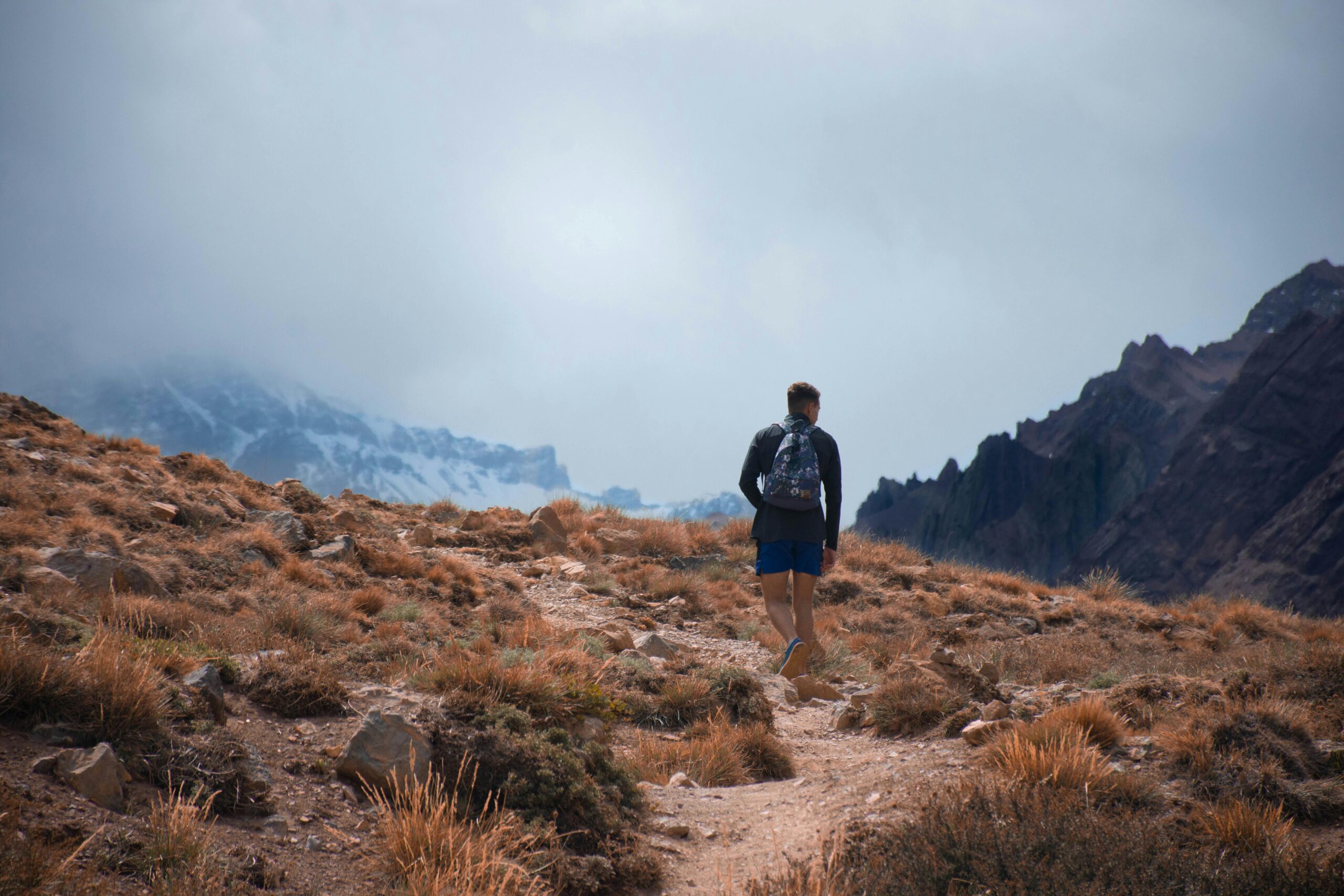 Man hiking alone on a rugged trail in the Andes mountains, San Rafael, Mendoza, Argentina.